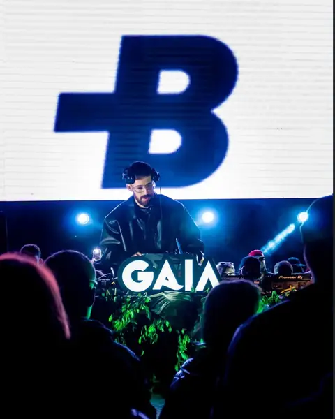 DJ no palco com painel de LED ao fundo e o público à frente