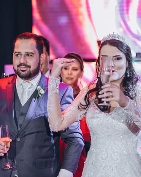Noivos brindando na festa de casamento, com painel de LED ao fundo